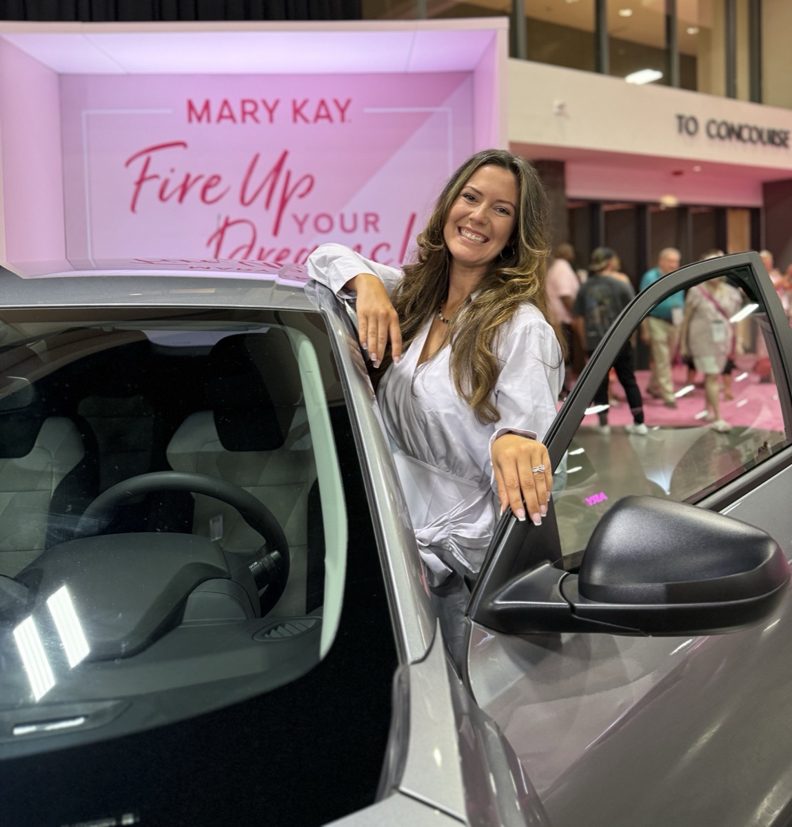Kaitlyn Stinespring at the Mary Kay Fire Up Your Dreams event with a Mary Kay career car